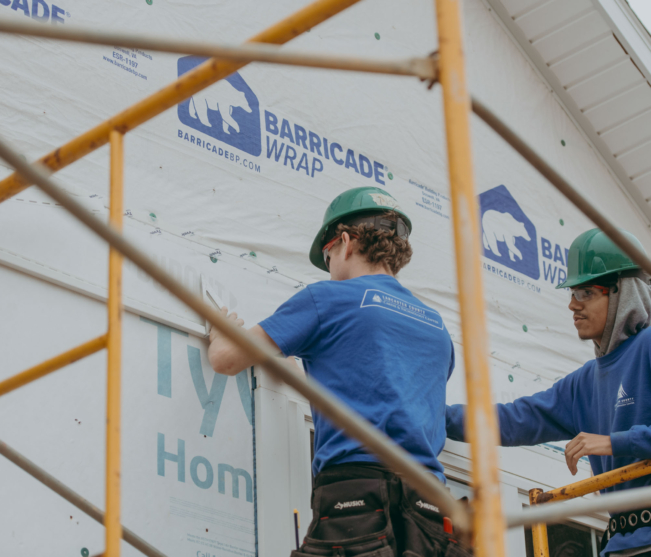 construction students attaching wrap on house