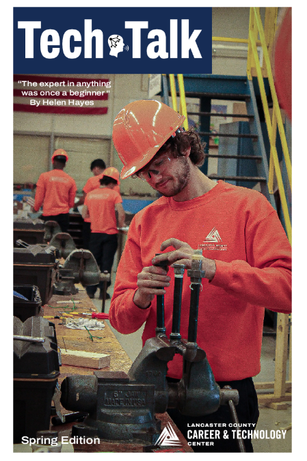 A plumbing student in orange and a hard hat