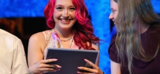 Student with certificate smiles at camera