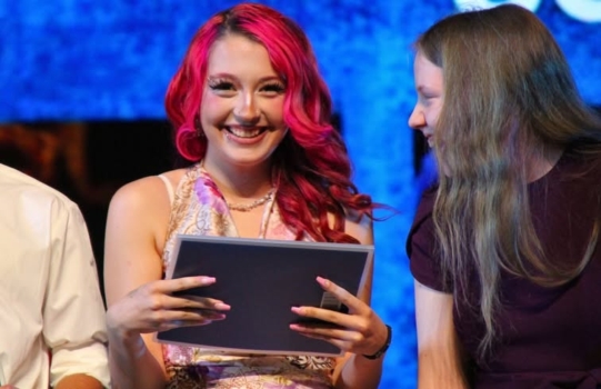 Student with certificate smiles at camera