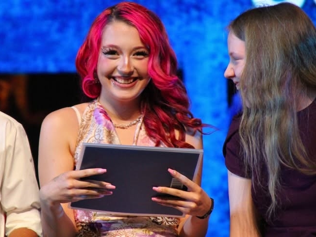 Student with certificate smiles at camera